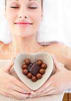 Bright woman holding a bowl in the shape of a heart with chocola