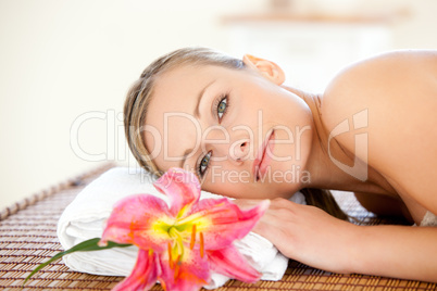 Close-up of a delighted woman lying on a massage table with a fl