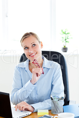 Pensive businesswoman holding glasses sitting at her desk