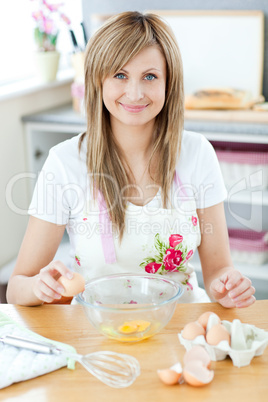 Joyful woman cooking in the kitchen and breaking eggs