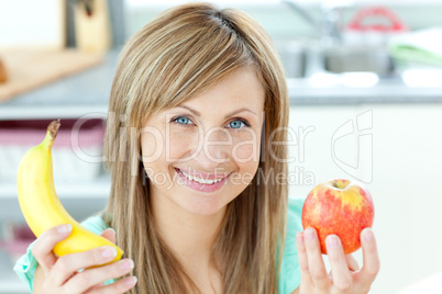Positive caucasian woman holing a banana and an apple in the kit