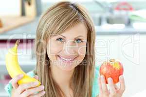 Positive caucasian woman holing a banana and an apple in the kit