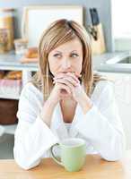 Thoughtful woman holding a cup of coffee in the kitchen