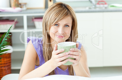 Glowing woman holding a cup of coffee in the kitchen