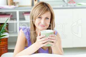 Glowing woman holding a cup of coffee in the kitchen