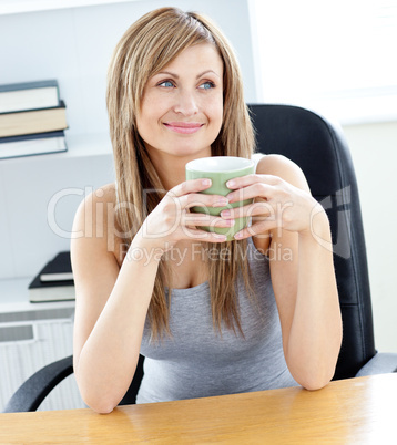 Relaxed businesswoman holding a cup of coffee in her office