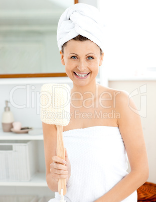 Charming young woman with a towel holding a brush in the bathroo
