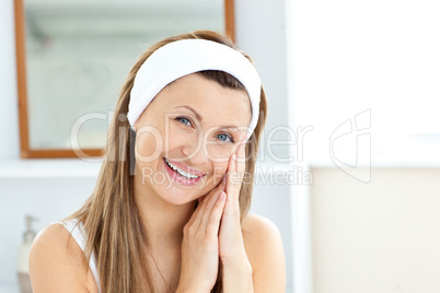 Charming young woman putting cream on her face in the bathroom