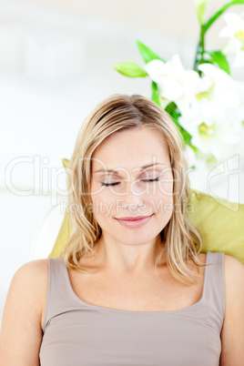Relaxed young woman with closed eyes lying on a sofa