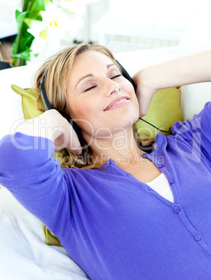 Relaxed caucasian woman listening to music with headphones lying