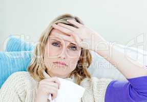 Diseased woman lying on a sofa with tissues and feeling her temp