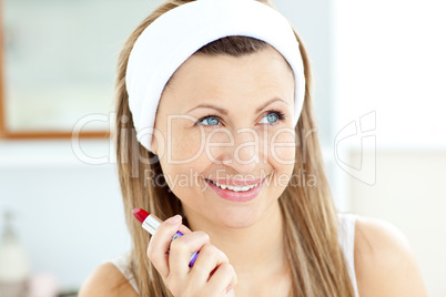 Bright young woman using a red lipstick in the bathroom