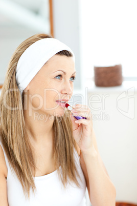 Serious young woman using a red lipstick in the bathroom