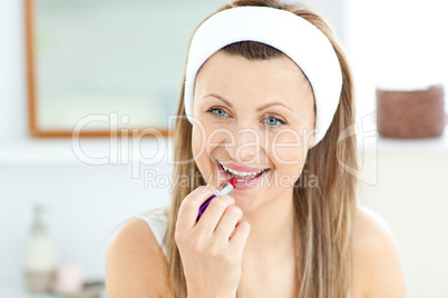 Pretty young woman using a red lipstick in the bathroom