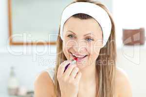 Pretty young woman using a red lipstick in the bathroom