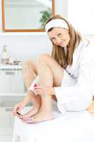 Happy caucasian woman varnishing her toenails in the bathroom