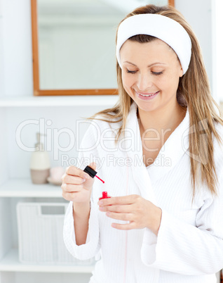 Bright caucasian woman varnishing her fingernails in the bathroo