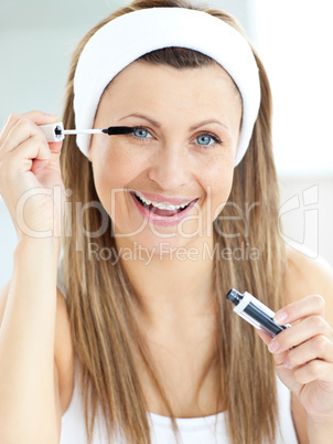 Delighted caucasian woman using mascara in the bathroom