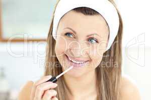 Radiant woman applying gloss on her lips in the bathroom