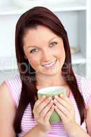 Cheerful woman holding a cup of coffee in the kitchen
