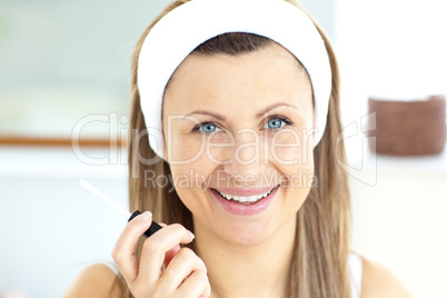 Positive woman applying gloss on her lips in the bathroom