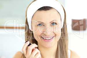 Positive woman applying gloss on her lips in the bathroom