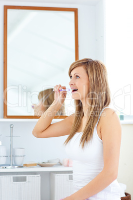 Blond young woman brushing her teeth in the bathroom