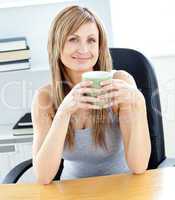 Glowing businesswoman holding a cup at her desk