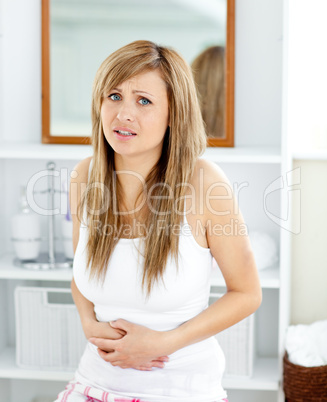 Blond woman having a stomachache in her bathroom