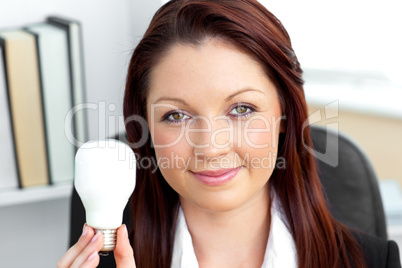 Confident young businesswoman holding a light bulb looking at th