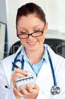 Confident female doctor smiling at the camera holding a notepad