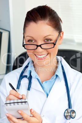 Self-assured female doctor smiling at the camera holding a notep