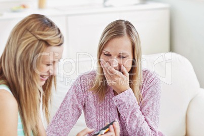 Two pretty female friends using a digital camera on a sofa