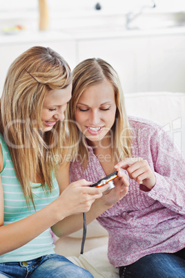 Two close female friends using a digital camera on a sofa