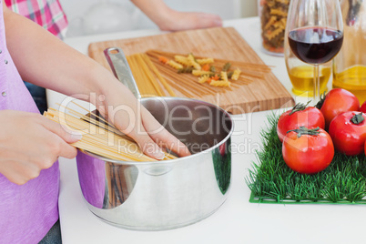 Close-up of two women cooking spaghetti in the kitchen