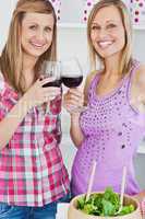 Two radiant women drinking wine after cooking in the kitchen