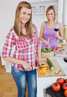 Two smiling women cooking together at home