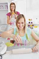 Smiling female friends baking pastry in the kitchen