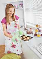 Cute young woman baking cookies in the kitchen