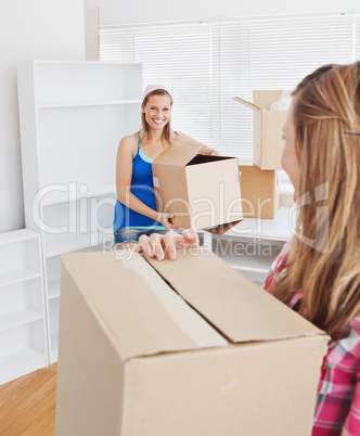 Two smiling women carrying boxes at home