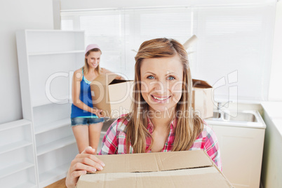 Two women carrying boxes at home