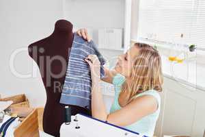Delighted young woman sewing clothes at home