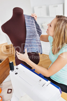 Serious young woman sewing clothes at home
