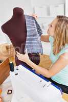 Serious young woman sewing clothes at home