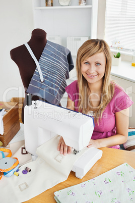 Positive young woman sewing clothes at home