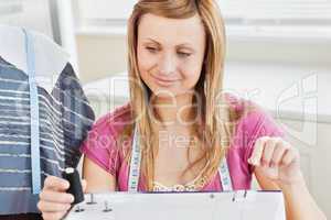 Concentrated young woman sewing clothes at home