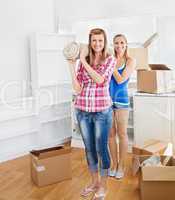 Two bright women carrying a carpet at home