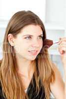 Radiant woman using a powder brush in her bathroom