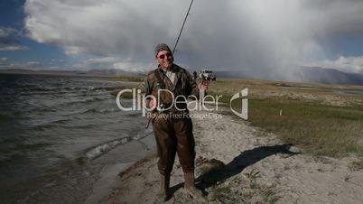Fisherman with spinning catching fish in mountain lake Dayan Nuur
