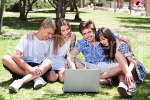 Friends enjoying movie in park on laptop
